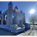 Image d'un chateau gonflable qui ressemble à un chateau mediéval, pierre grise et toit bleu